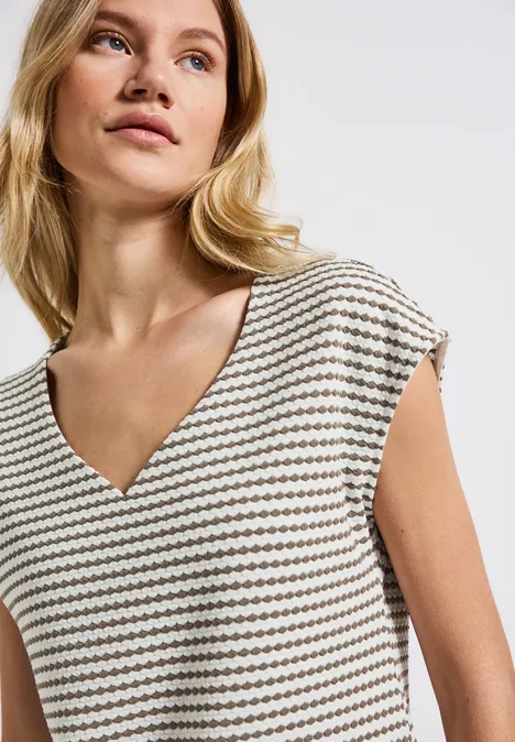 Frau mit blondem Haar trägt gestreiftes V-Ausschnitt-Shirt.